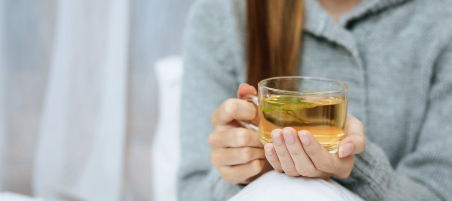 Mulher bebendo chá para o fígado para aliviar o estômago pesado.