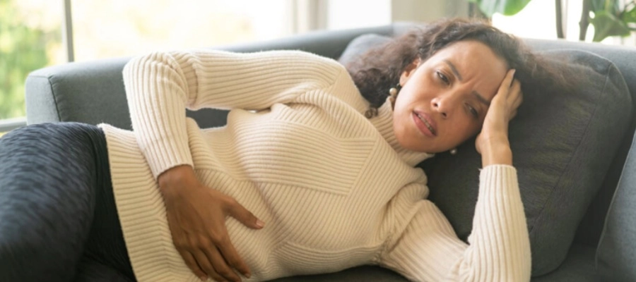 uma mulher deitada de lado no sofá com a mão na barriga