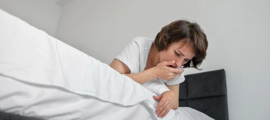 mulher deitada na cama com enjoo matinal e ânsia de vômito