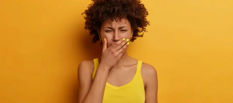 Mulher com a mão na boca expressando gosto ruin