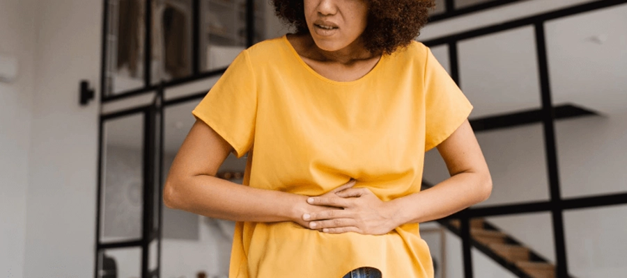 mulher com dor de barriga coloca as mãos sobre o abdômen