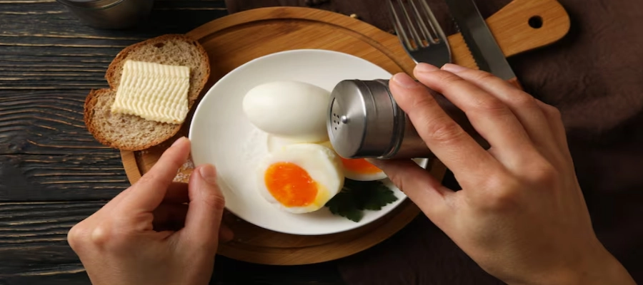 pessoa temperando ovos cozidos para comer no café da manhã