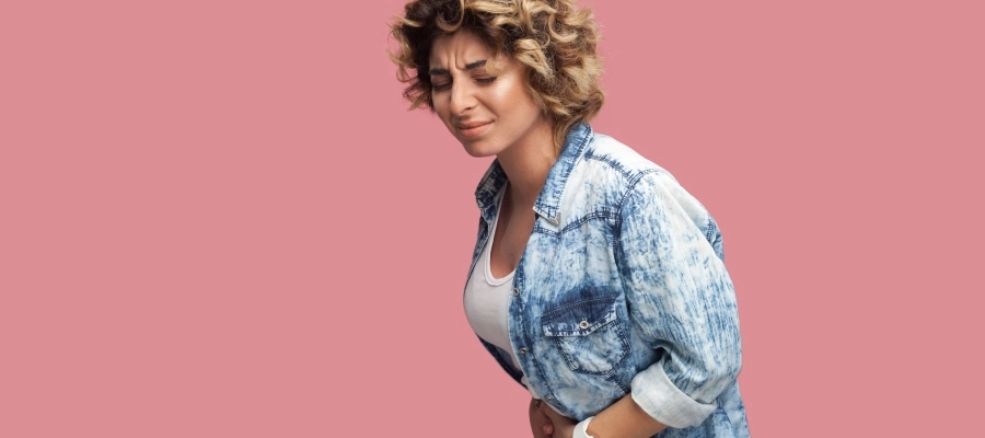 uma mulher em uma camisa jeans sente cólica