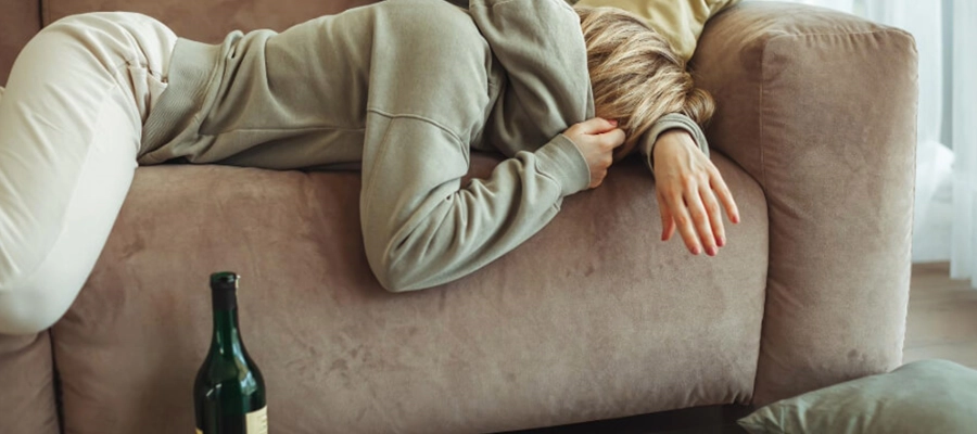mulher dormindo no sofá após passar a noite bebendo vinho