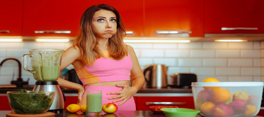 Mulher segurando o abdômen, indicando necessidade de desinchar a barriga​. 