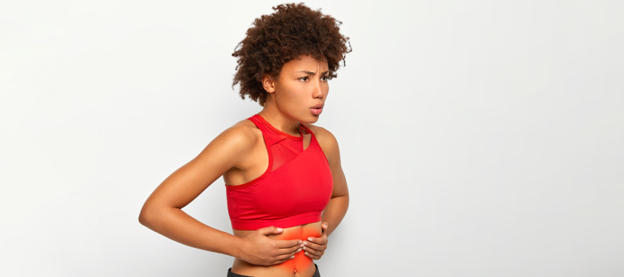 Mulher segurando a parte abdominal onde fica o fígado.