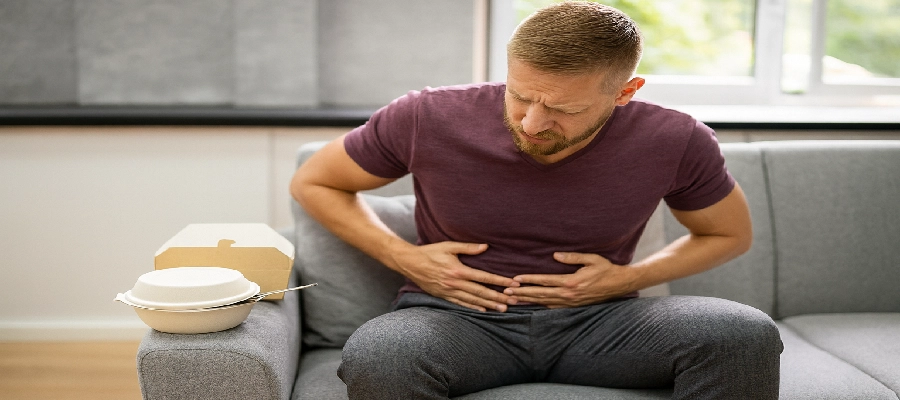 Homem sentindo o estômago queimando após comer. 
