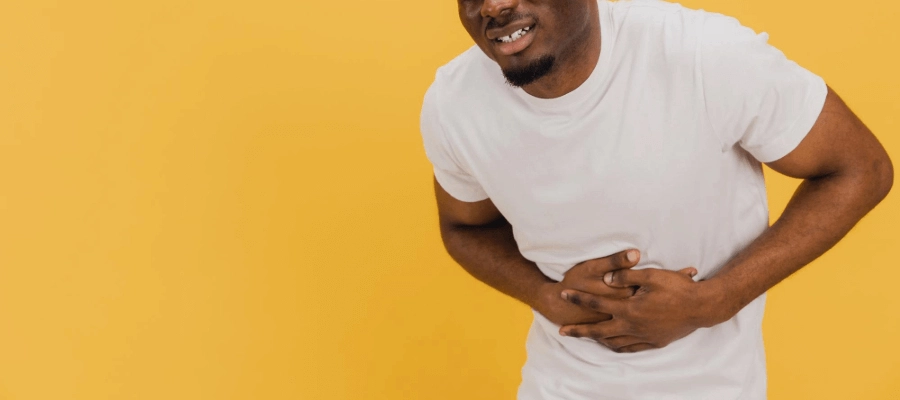 homem com as mãos juntas sobre o abdômen e expressão de dor
