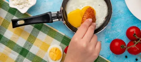 Pessoa passando pão em ovo dentro de uma frigideira.