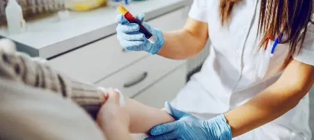 Pessoa coletando sangue em laboratório de exames.